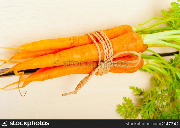 fresh baby carrots bunch tied with rope on a rustic table