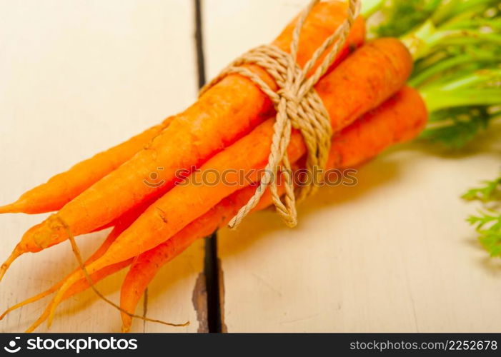 fresh baby carrots bunch tied with rope on a rustic table