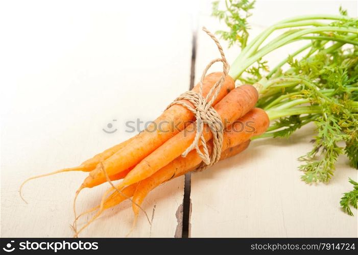 fresh baby carrots bunch tied with rope on a rustic table