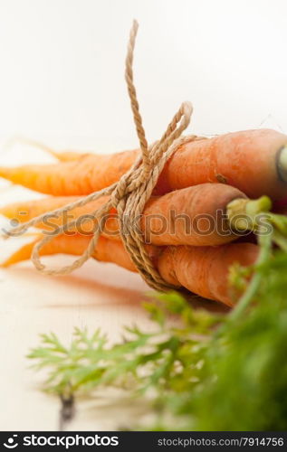 fresh baby carrots bunch tied with rope on a rustic table