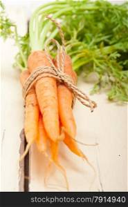 fresh baby carrots bunch tied with rope on a rustic table