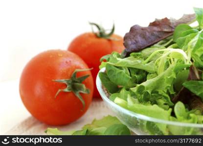 Fresh baby greens salad and tomatoes on white background