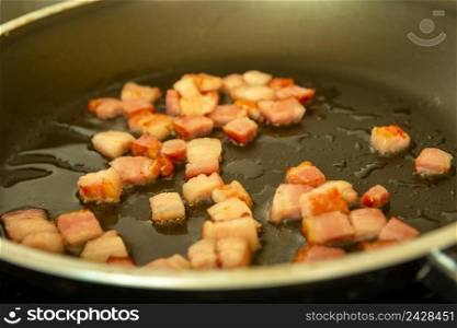 Fresh bacon fried in oil in a pan