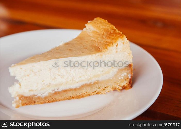 Fresh bake cheese pie on white plate on wood table close up whole peice. Beautiful layer of cheese pie cake