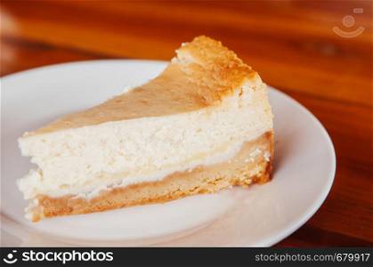 Fresh bake cheese pie on white plate on wood table close up whole peice. Beautiful layer of cheese pie cake