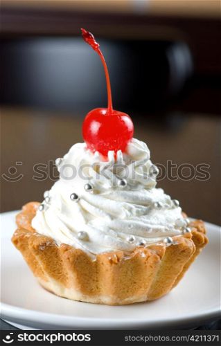 fresh baked cherry cupcake on a dark wooden background