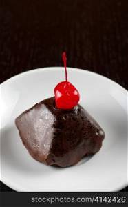 fresh baked chocolate cupcake with cherry on a wooden table