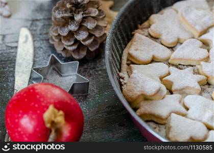 Fresh baked homemade apple pie on a wood table with cutter and apples.