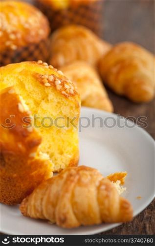 fresh baked muffin and croissant mignon on old wood table