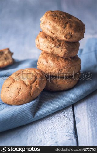 Fresh baked pile of rye bread buns on a blue kitchen towel. Close-up image of healthy bread rolls in a stack. A heap of homemade cute buns.