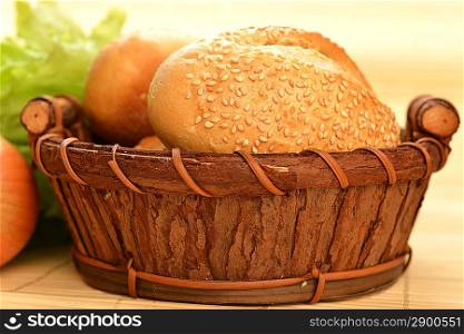 fresh baked rolls in a basket on wooden background