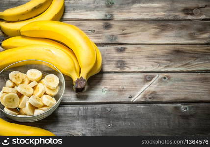 Fresh bananas and banana slices in a glass bowl. On a wooden background.. Fresh bananas and banana slices in a glass bowl.