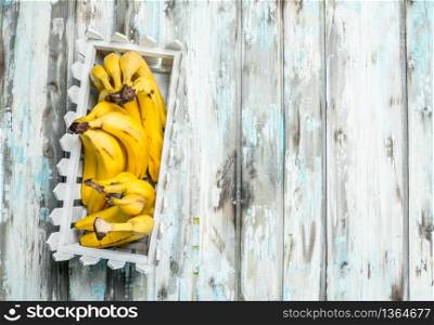 Fresh bananas in a white plastic basket. On a white wooden background.. Fresh bananas in a white plastic basket.