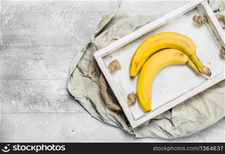 Fresh bananas in a wooden box. On white rustic background.. Fresh bananas in a wooden box.