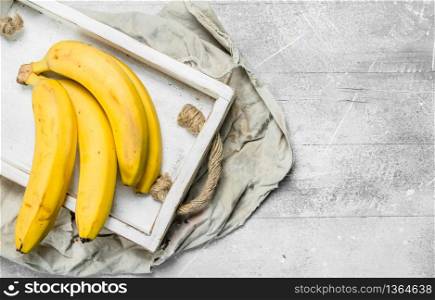 Fresh bananas in a wooden box. On white rustic background.. Fresh bananas in a wooden box.