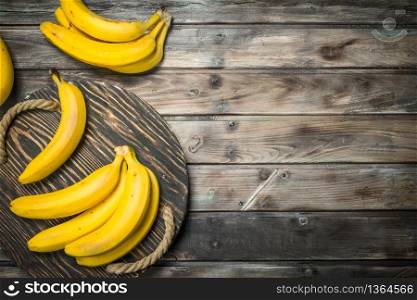 Fresh bananas on a black old wooden tray. On a dark wooden background.. Fresh bananas on a black old wooden tray.