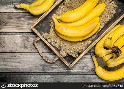 Fresh bananas on the bag in the old dressing. On a black wooden background.. Fresh bananas on the bag in the old dressing.