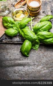 Fresh basil leaves with olives oil and salt on rustic wooden background