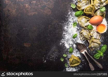 fresh basil tortellini with ingredients on a dark underground, top view