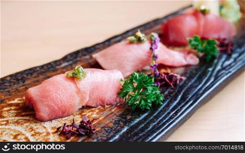 Fresh beautiful pieces of Japanese Otoro tuna sushi on craft ceramic plate, close up shot