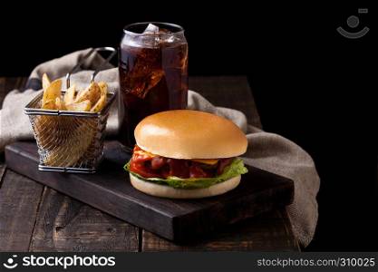 Fresh beef burger with potato wedges and glass of cola soda drink on wooden background