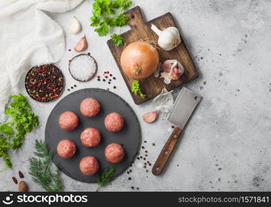 Fresh beef meatballs on stone board with pepper, salt and garlic on light background with dill,parsley and dill and onion. Top view