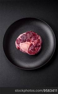 Fresh beef ossobuco steak with salt, spices and herbs on textured concrete background