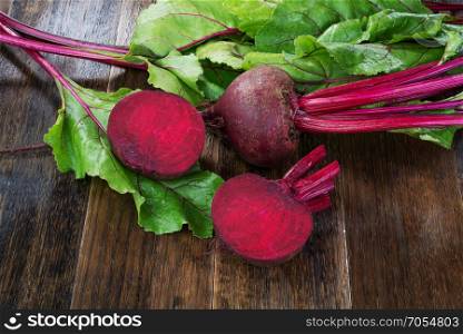 Fresh beetroots with leaves on wooden rustic table.Whole and cut beetroots