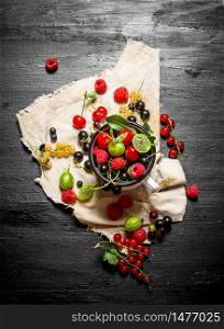 Fresh berries in a cup on the old fabric. On a black wooden background.. Fresh berries in a cup on the old fabric.