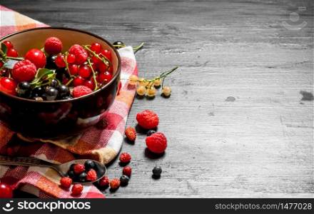 Fresh berries in a cup on the old fabric. On a black wooden background.. Fresh berries in a cup on the old fabric.