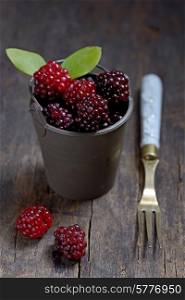 Fresh berries in small bucket on wooden background
