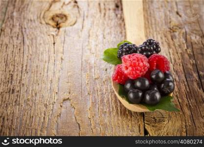fresh berries in wooden spoon on wooden table