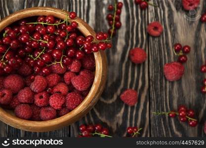 Fresh berries on wooden table. Fresh berries raspberry and red currant in bowl on wooden table