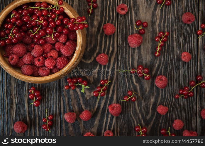 Fresh berries on wooden table. Fresh berries raspberry and red currant in bowl on wooden table