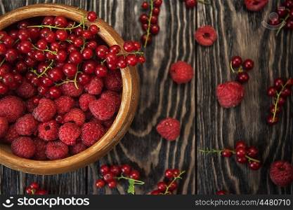 Fresh berries raspberry, red currant and plums on wooden table