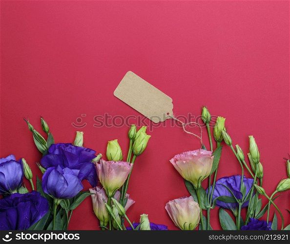 fresh blooming flowers Eustoma Lisianthus and empty paper tag on red  background, top view, copy space