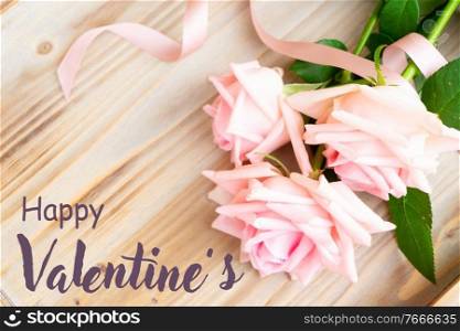 fresh blooming pink roses laying on wooden table, with happy valentines day greeting. pink roses on table