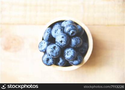 Fresh blueberries fruit in bowl on the wooden table background , top view