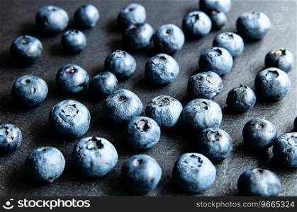Fresh blueberries in a glass jar on a black board. Blueberries for a healthy diet and vegetarians