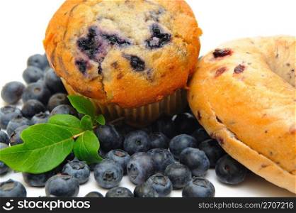 Fresh blueberries surround a single blueberry muffin and a bagle on a light background. Muffin And Bagle