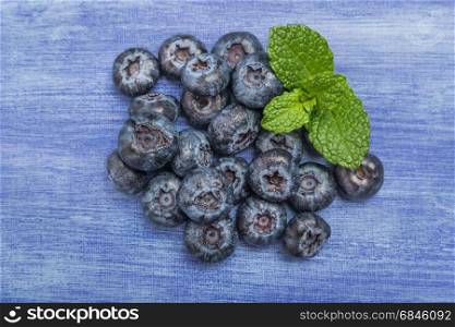 Fresh blueberries with mint leaf on rustic textured background with copy space