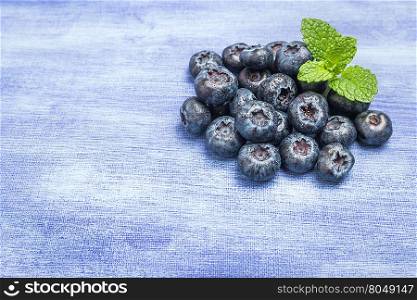 Fresh blueberries with mint leaf on rustic textured background with copy space
