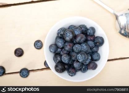 fresh blueberry on a bowl with silver spoon over wood table