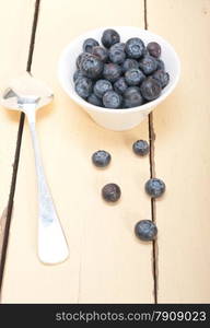 fresh blueberry on a bowl with silver spoon over wood table