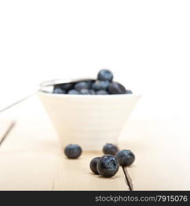 fresh blueberry on a bowl with silver spoon over wood table