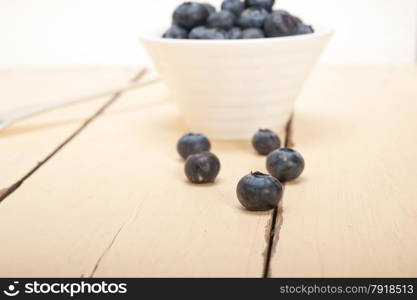 fresh blueberry on a bowl with silver spoon over wood table