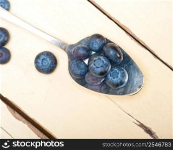 fresh blueberry on silver spoon over a white rustic wood table