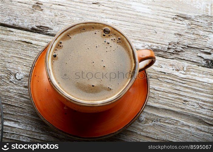 fresh boiled coffee served in beautiful prange cup around old style wooden background . close up. flat lay 