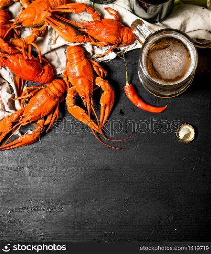 Fresh boiled crawfish with beer on the old fabric. On a black chalkboard.. Fresh boiled crawfish with beer on the old fabric.