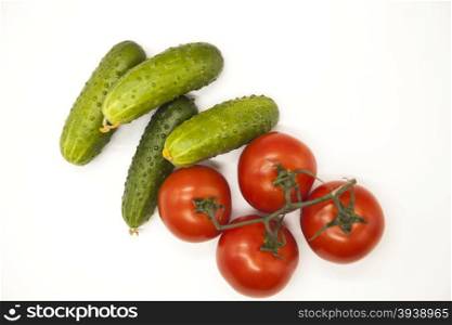 Fresh branch of red Sicilian ripe tomatoes and cucumbers on a white background. Fresh branch of red Sicilian ripe tomatoes and cucumbers on a white background.